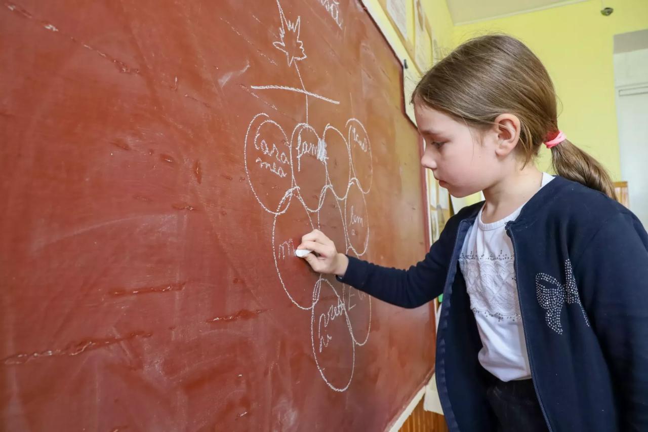 A young Moldovan girl draws on a chalkboard.