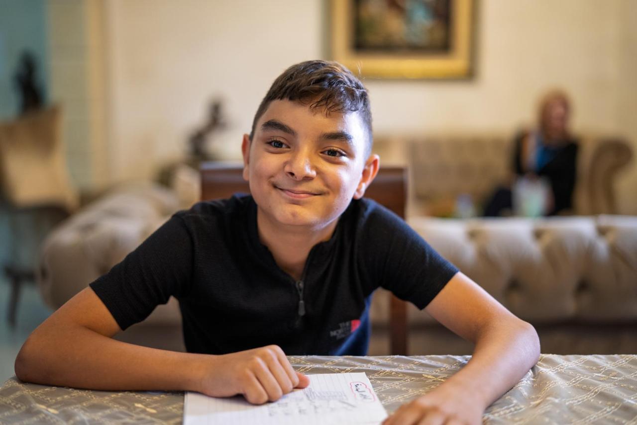 A young boy in Lebanon sits at a table.