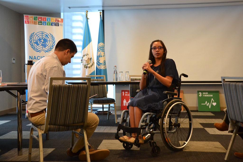 A female disability-inclusion leader in Guatemala speaks with a high-level UN official at a workshop.