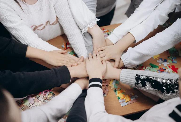 A group of girls in Moldova join their hands in a circle.