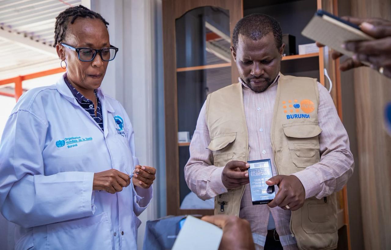 A female and male health worker in Burundi examine a box of medications.