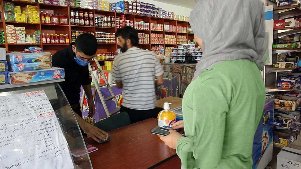 امرأة تدفع لأمين الصندوق مقابل مشترياتها وتستخدم قسيمتها الإلكترونية.