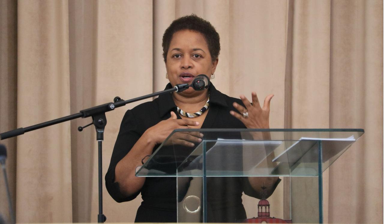 Allyson West, Ministra de Administración Pública y Transformación Digital de Trinidad y Tobago, habla por un micrófono en un podio en el escenario.