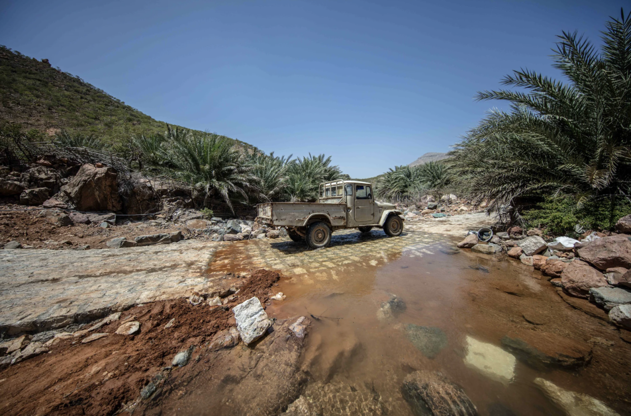 A truck driving through a partially destroyed street.