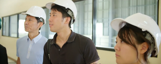 Three people with white construction helmets look off camera. 