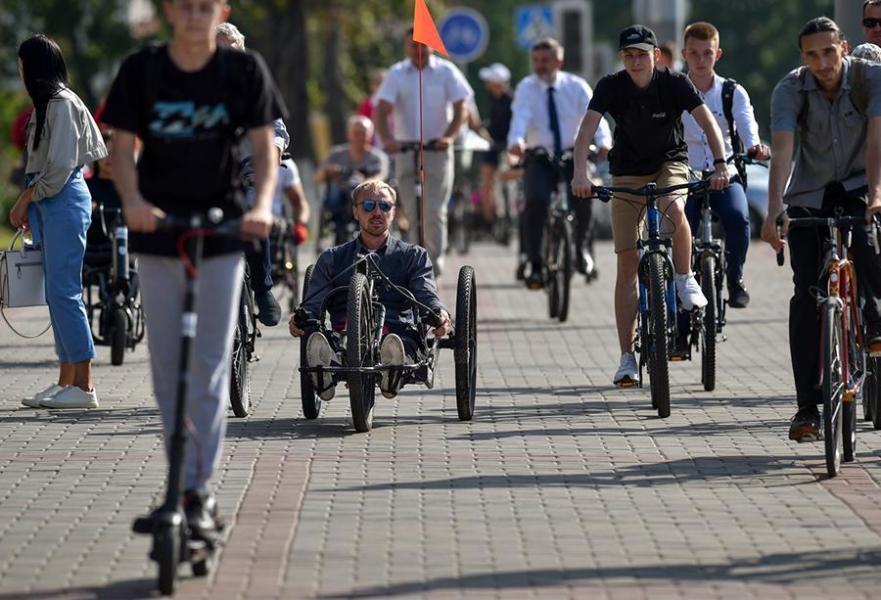A person rides a handcycle next to people on bikes and a scooter. 