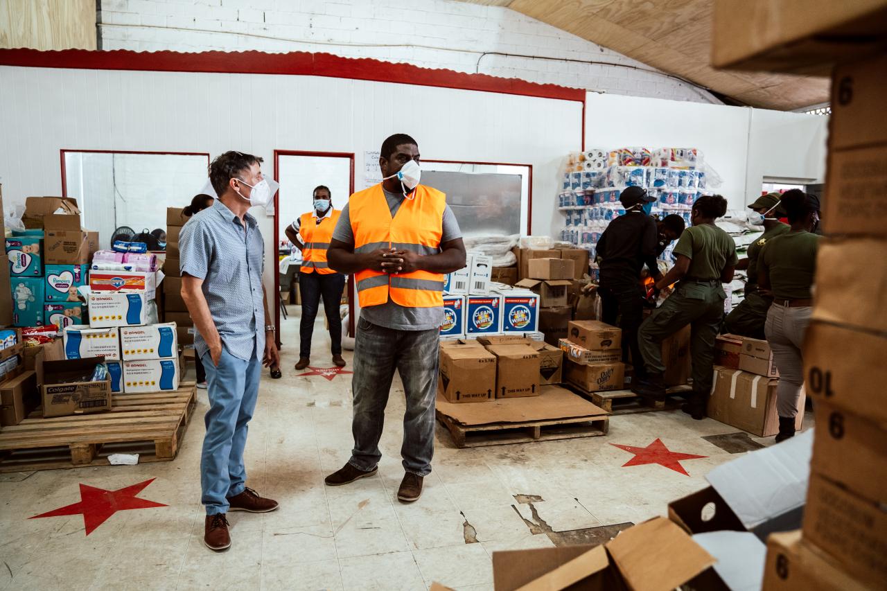 Didier Trebucq, le Coordonnateur résident des Nations Unies pour la Barbade et les Caraïbes orientales, discute avec un homme portant un gilet orange dans les locaux d’un site d'entreposage de l'aide humanitaire fournie par l'ONU peu après l'éruption du volcan la Soufrière, à Saint-Vincent-et-les-Grenadines, le 9 avril 2021.