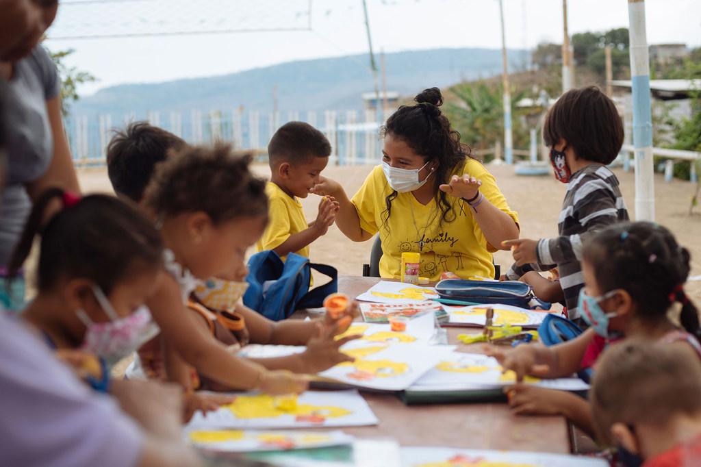 Un grupo de niños y niñas realiza una actividad de manualidades junto a su maestra.