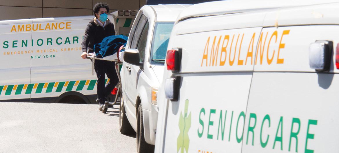 A healthcare worker at a hospital moves a body into a vehicle. 