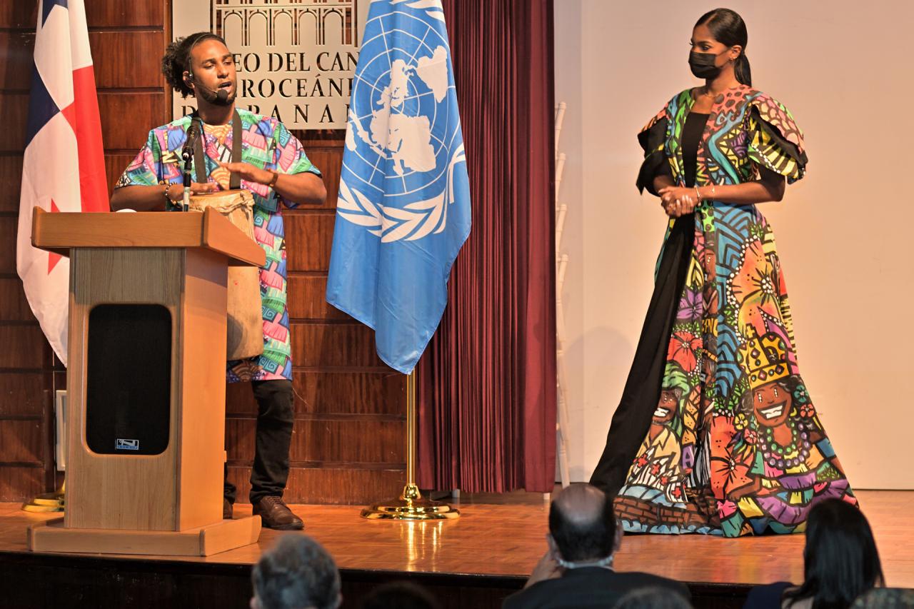 Sur la scène du Musée du canal interocéanique de Panama, devant les drapeaux de l’ONU et d Panama, le percussionniste Jorge Montenegro chante en jouant des percussions aux côtés de Nicole Pinto, vêtue d’une robe traditionnelle panaméenne aux couleurs flamboyantes.
