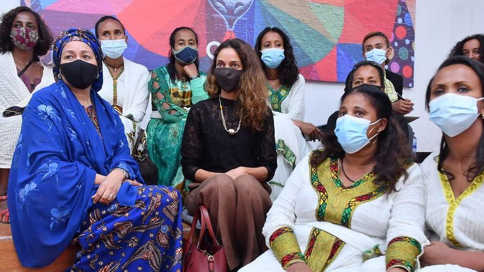 La Vicesecretaria General, Amina Mohammed, con una mascarilla protectora rodeada de un grupo de jóvenes sentadas con mascarillas.