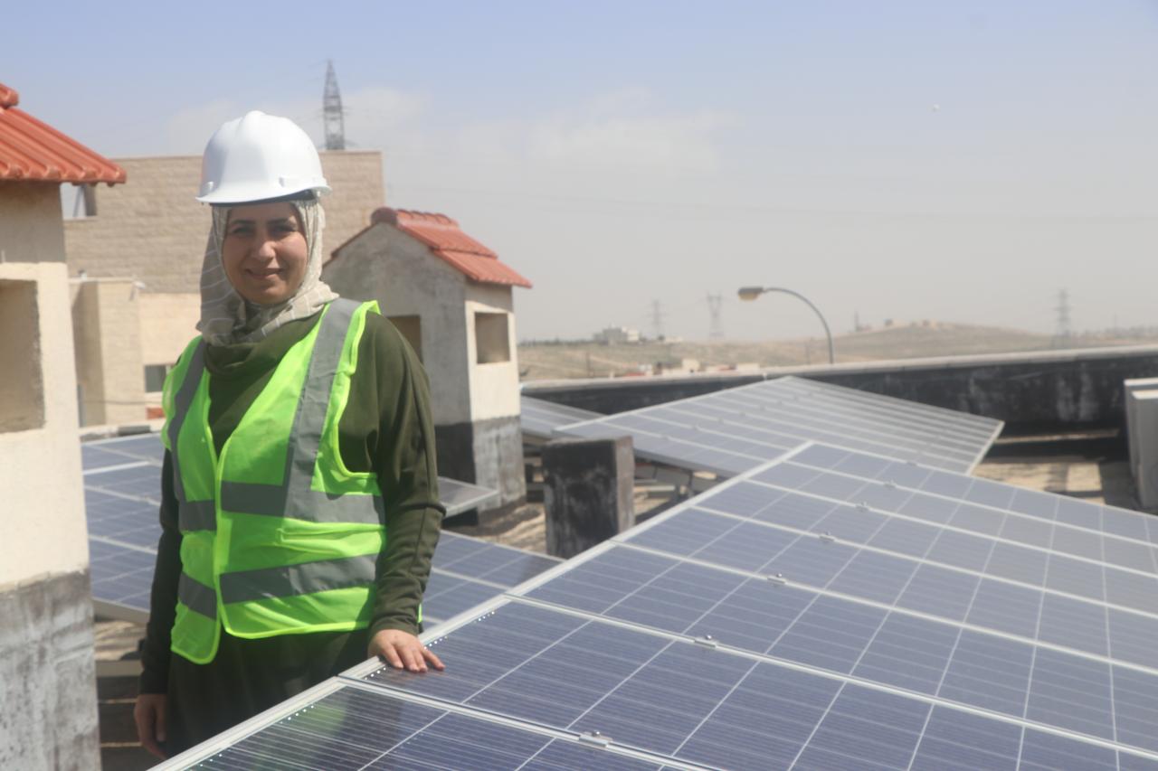 A woman standing near the solar panels and looking directly into the camera.