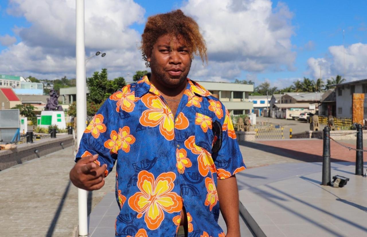 A man wears a blue Hawaiian shirt on a sunny day. 