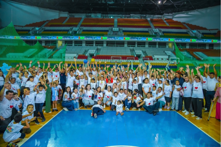 A crowd of over hundred people are posing for the camera in the middle of a sports hall.