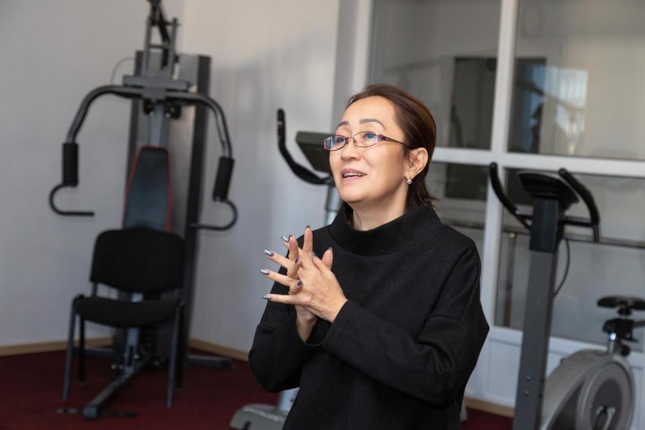 Woman in a black shirt with glasses sitting in a gymnasium