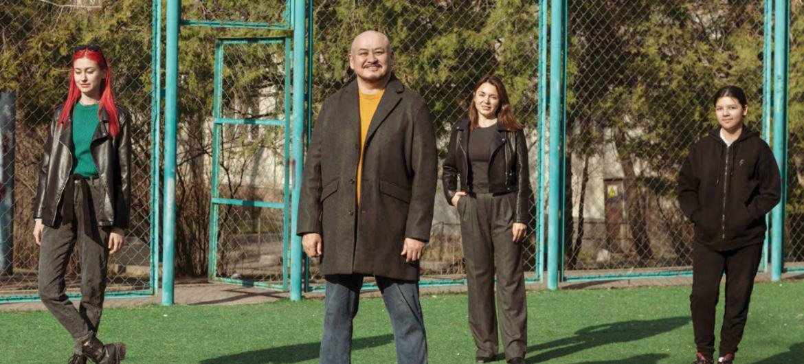 Молодые люди, три женщины и мужчина, позируют на спортивной площадке