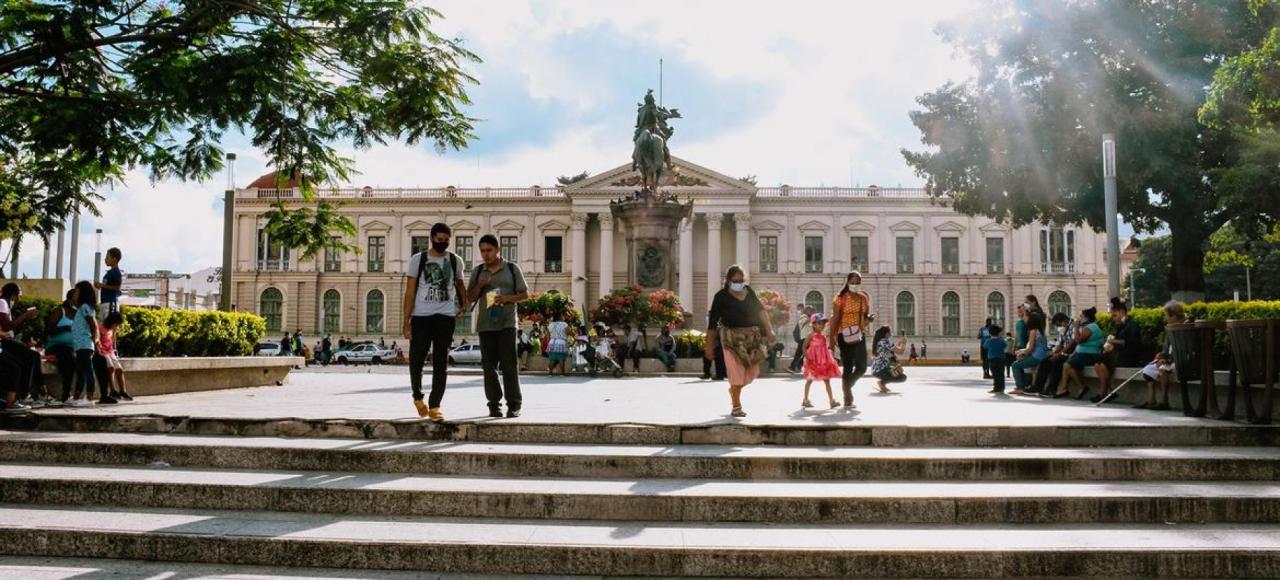 A wide building, like a public square, with people in masks walking through it