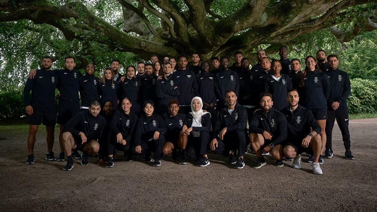 A group of sportspersons in black uniforms under a tree
