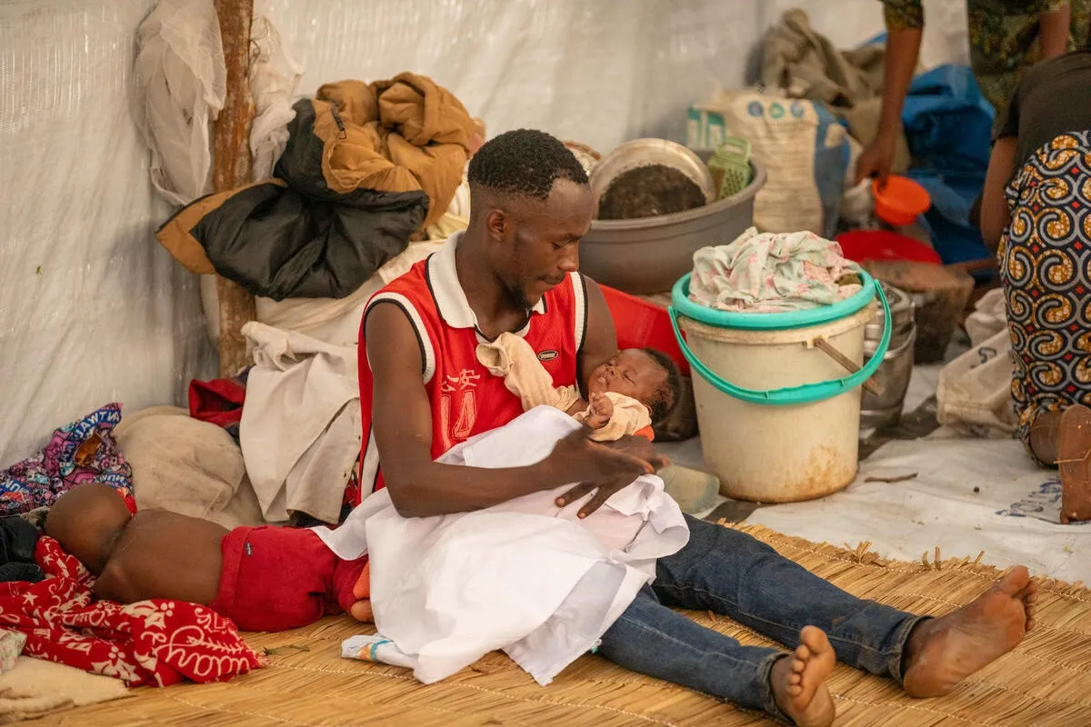 Ishara tient son bébé sur ses genoux tandis qu'un autre enfant dort à côté de lui dans le camp de réfugiés de Musenyi, dans le sud du Burundi.