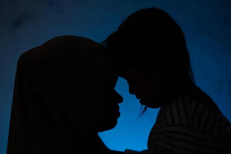 The silhouette of a woman embracing her young daughter.