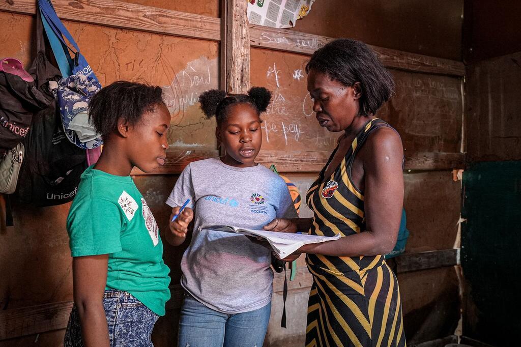 Les enfants déplacées poursuivent ses études avec l’appui de sa mère et d’une enseignante, symbole de l’éducation comme espoir face à la crise en Haïti.