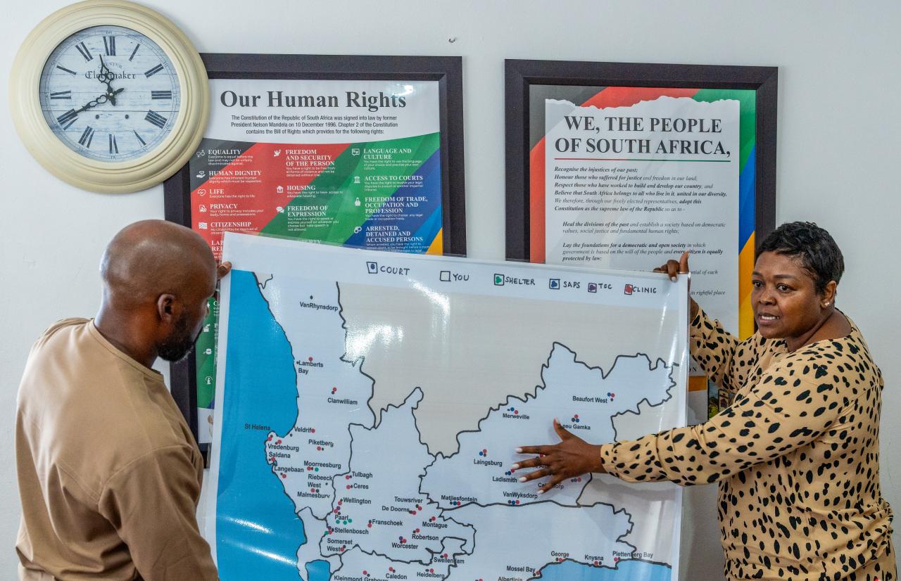 Employees of a civil society organization in South Africa show a map of gender-based violence support services.
