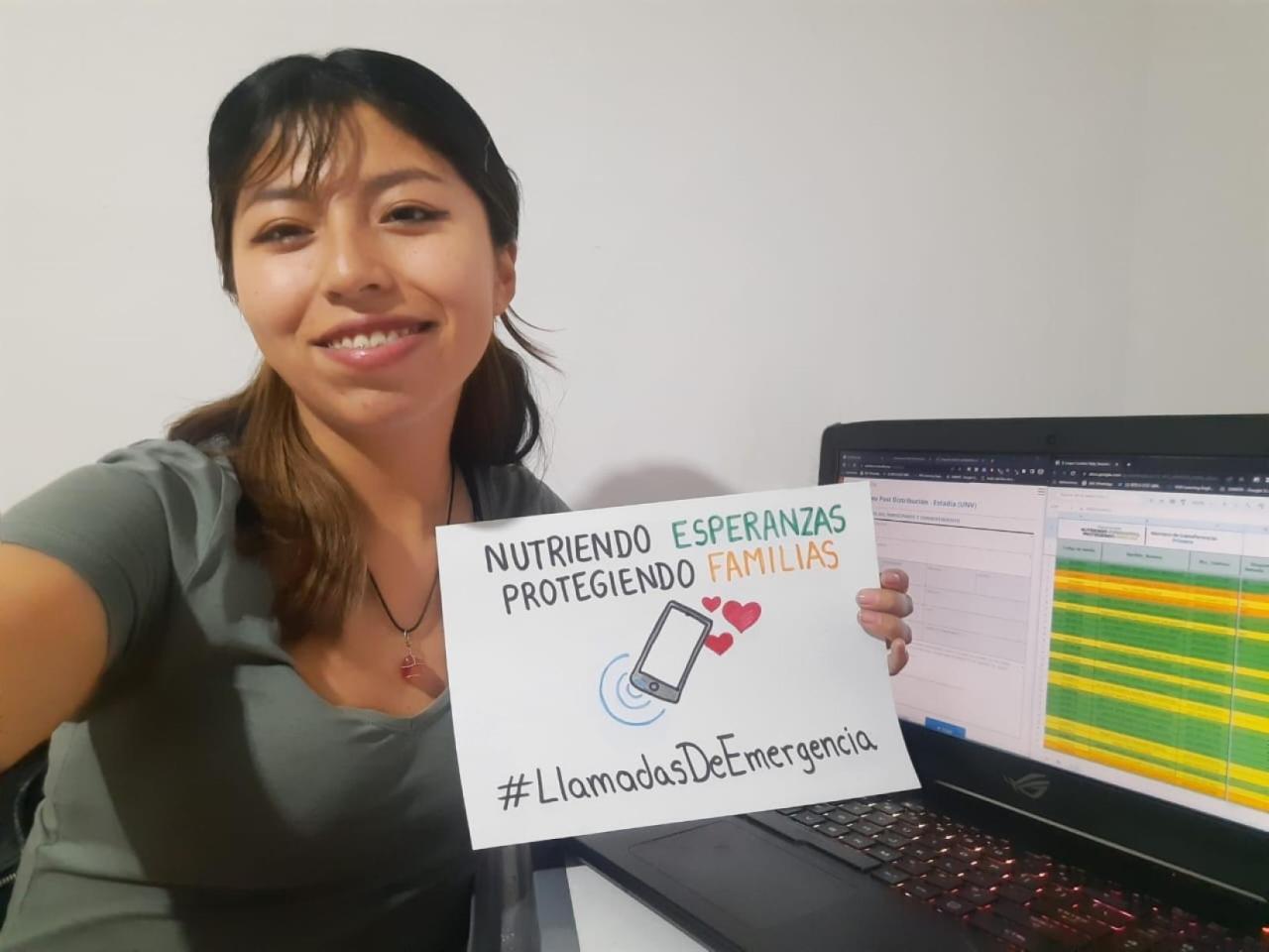Una mujer sonríe a cámara mientras sostiene un cartel sobre llamadas de emergencia.