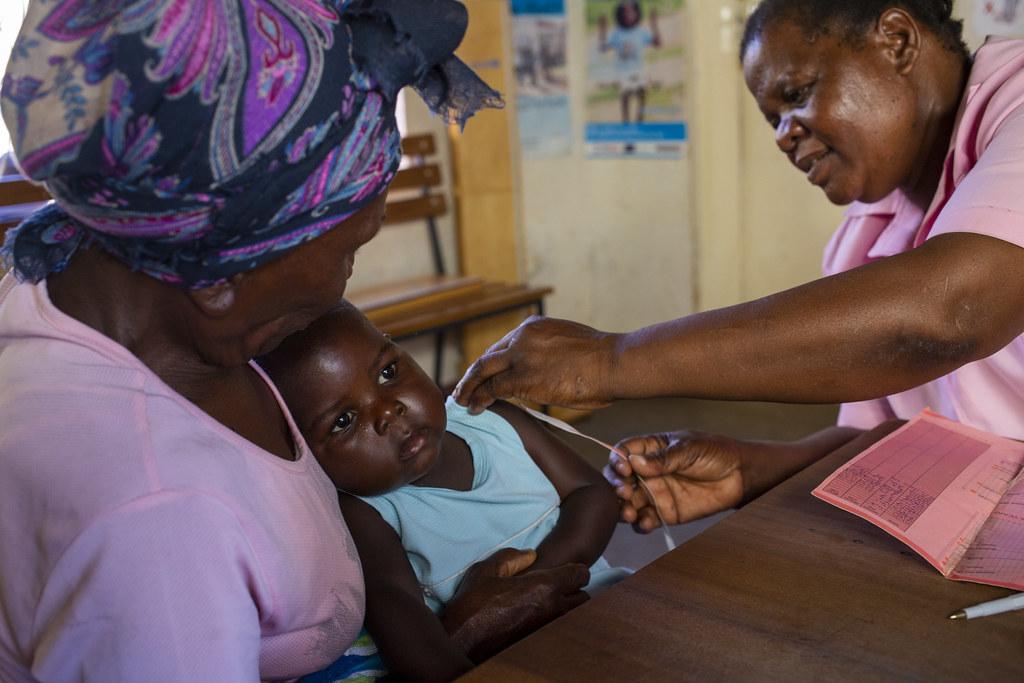 A woman in Zimbabwe holds her granddaughter as she receives a vaccine. 