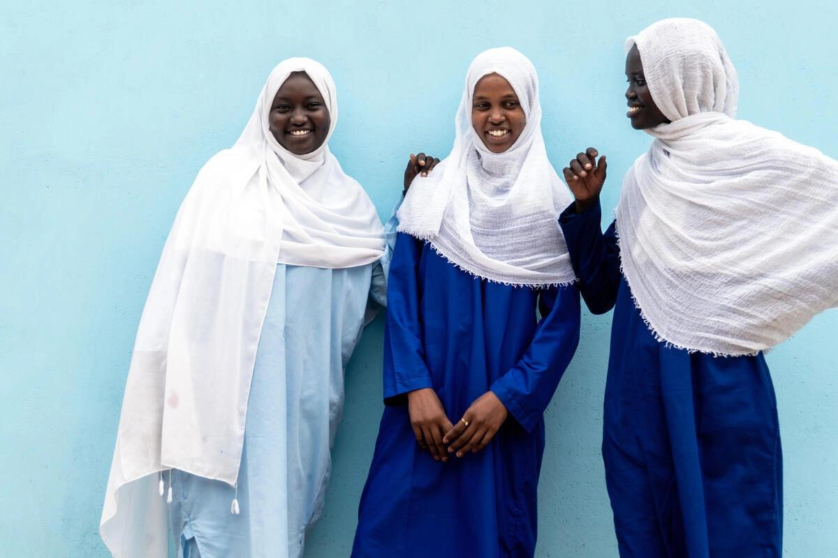Three Sudanese girls smile for a photo together.