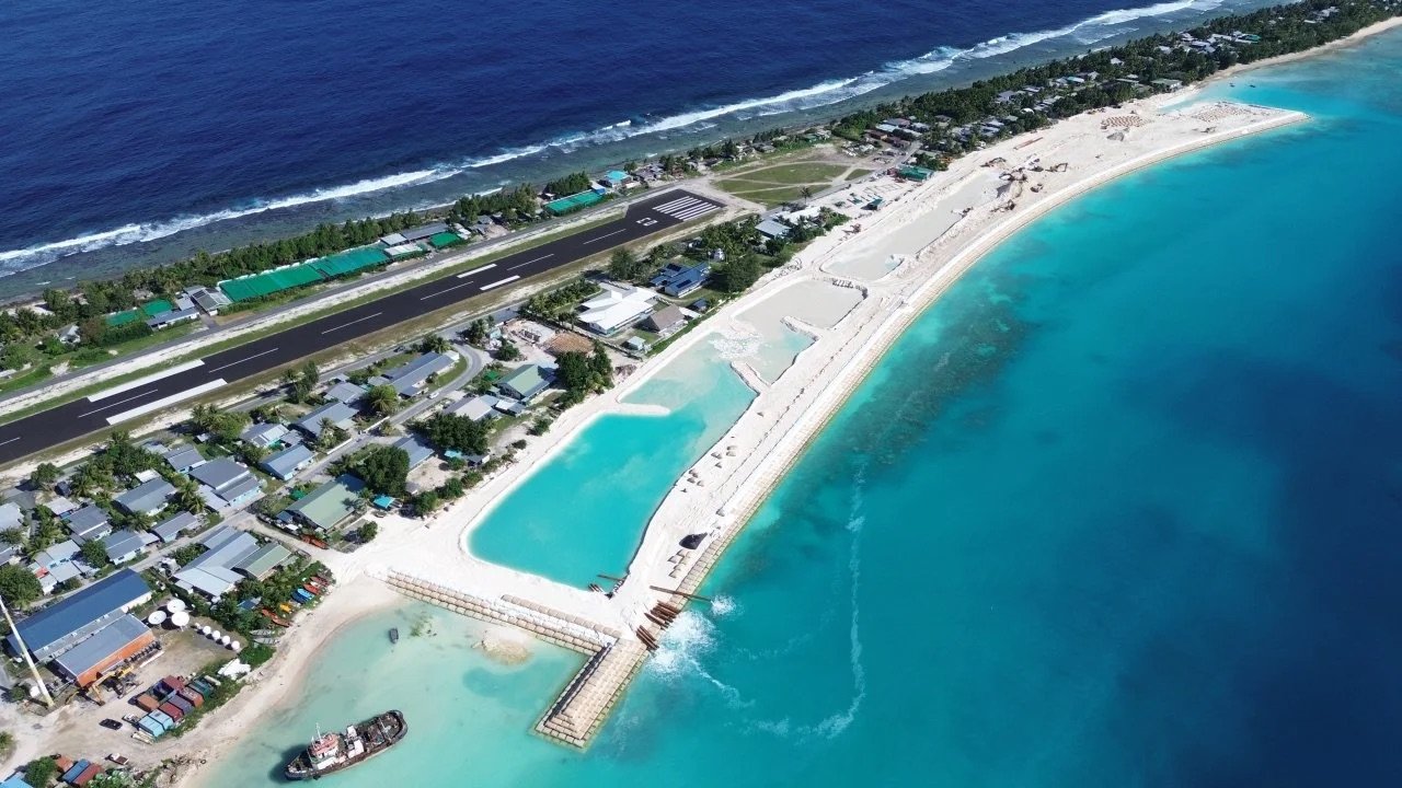 Vista aérea de una isla con obras de protección costera y una pista de aterrizaje.