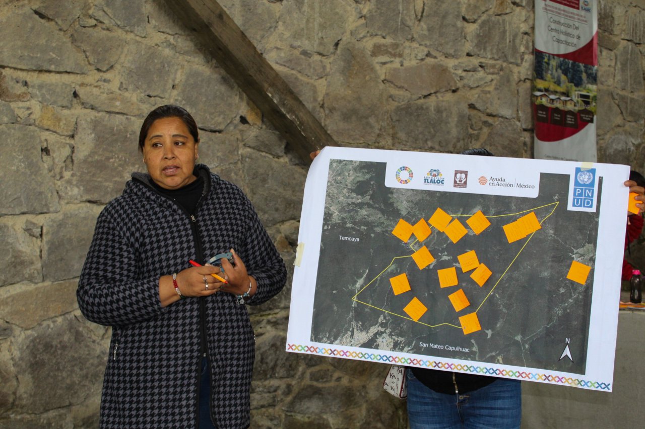 A woman in Mexico stands in front of a map.