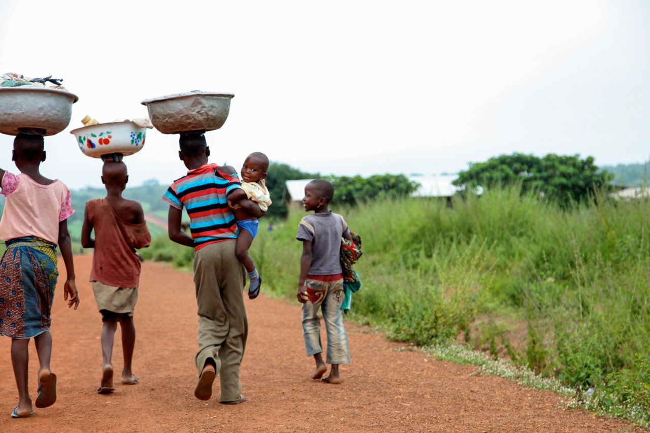 Youth in Benin walk with bowls on their head.