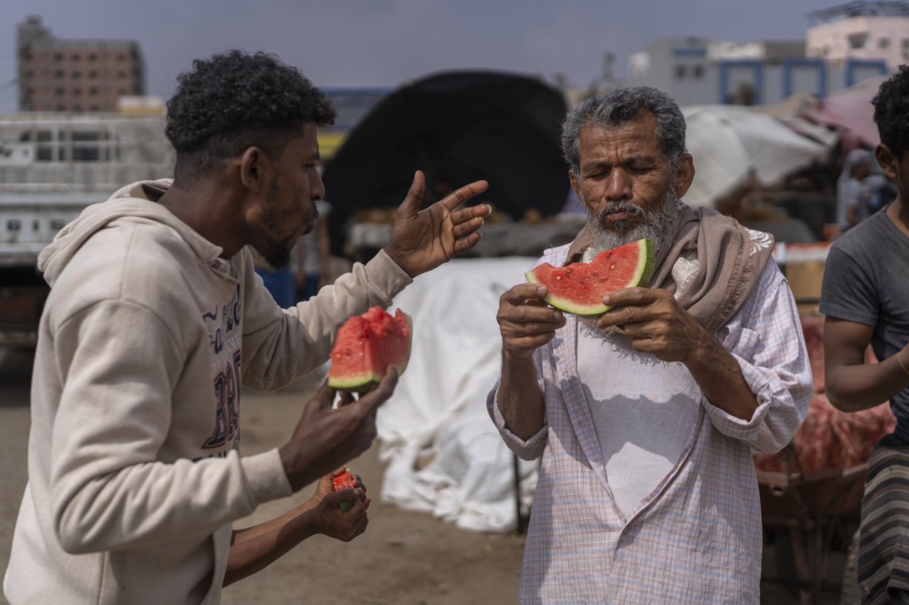 Two men in Yemen eat watermelon.