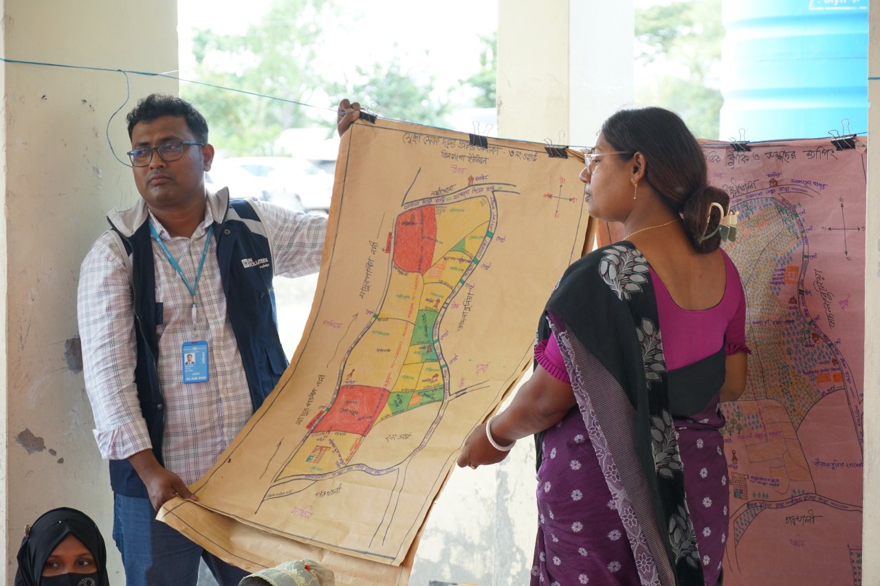 A UN Volunteer and local community member present a diagram to local community members in Bangladesh.