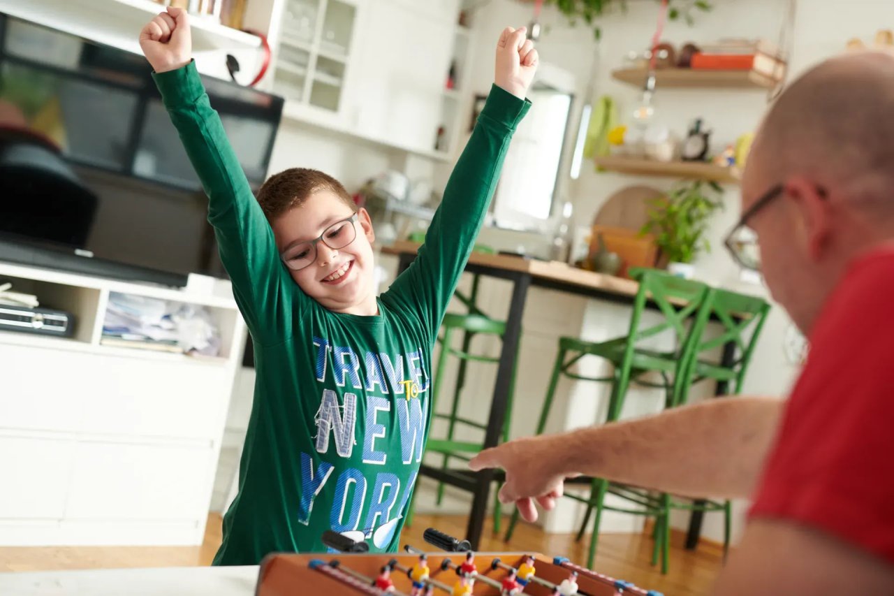 A happy boy in Montenegro plays foosball with his father.