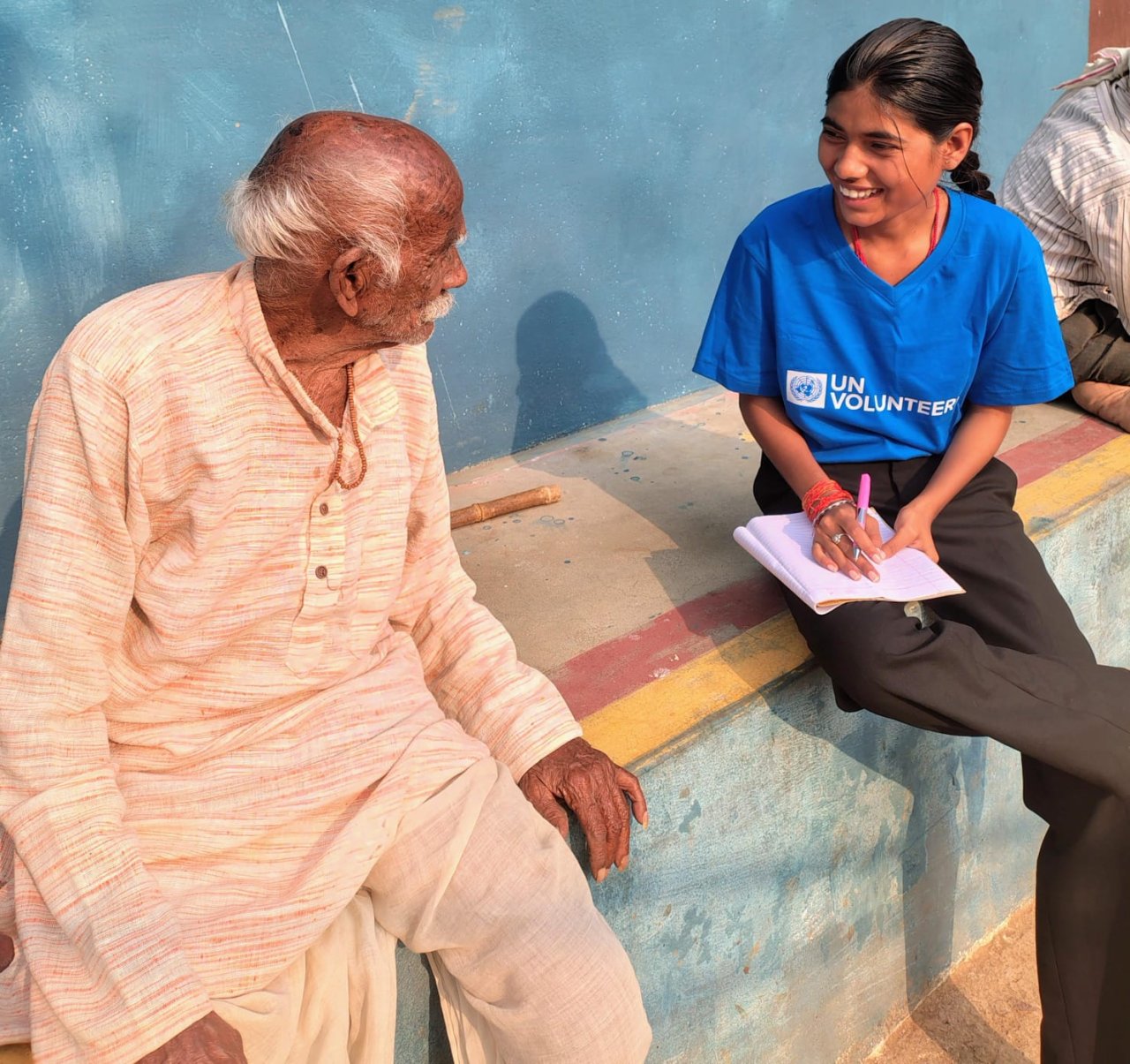 A young UN Volunteer in India speaks to an elderly man.