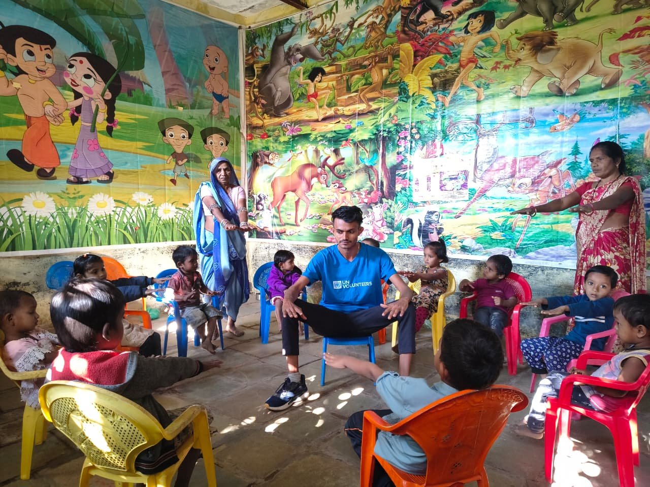 A young UN Volunteer in India sits in a school with students.