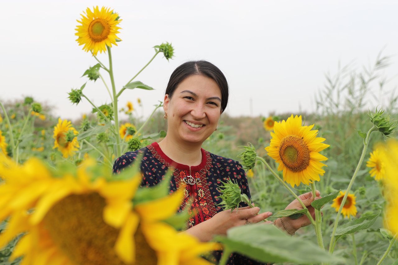 A woman in Turkmenistan stands in a sunflower field.