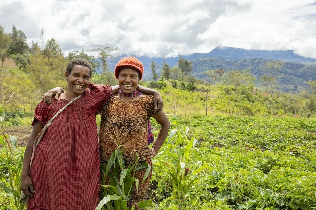 Two women stand in a field in Papua New Guinea