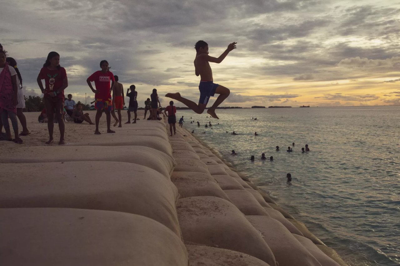 A boy jumps into the ocean.