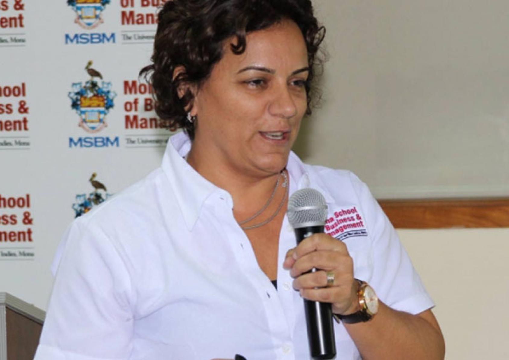 La Dra. Lila Rao-Graham hablando por un micrófono en un evento.