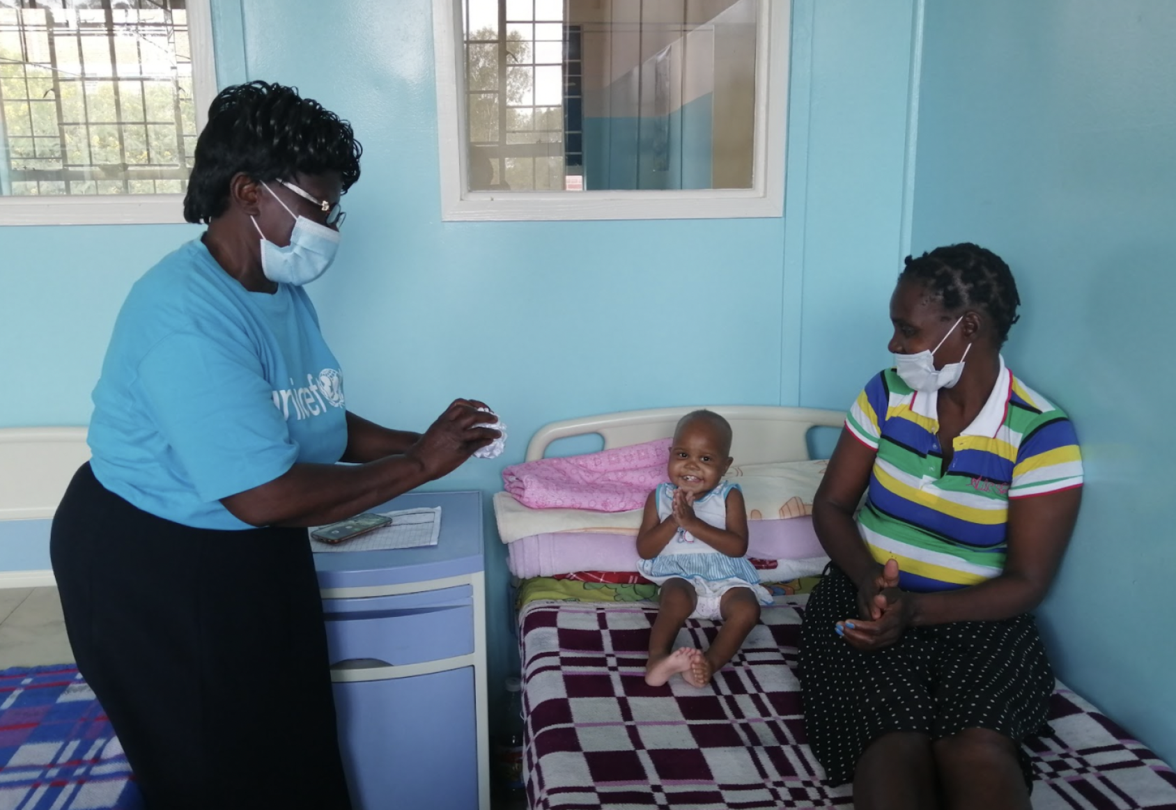 أم وطفل يجلسان على سرير ويتحدثان إلى ممثلة من اليونيسف.