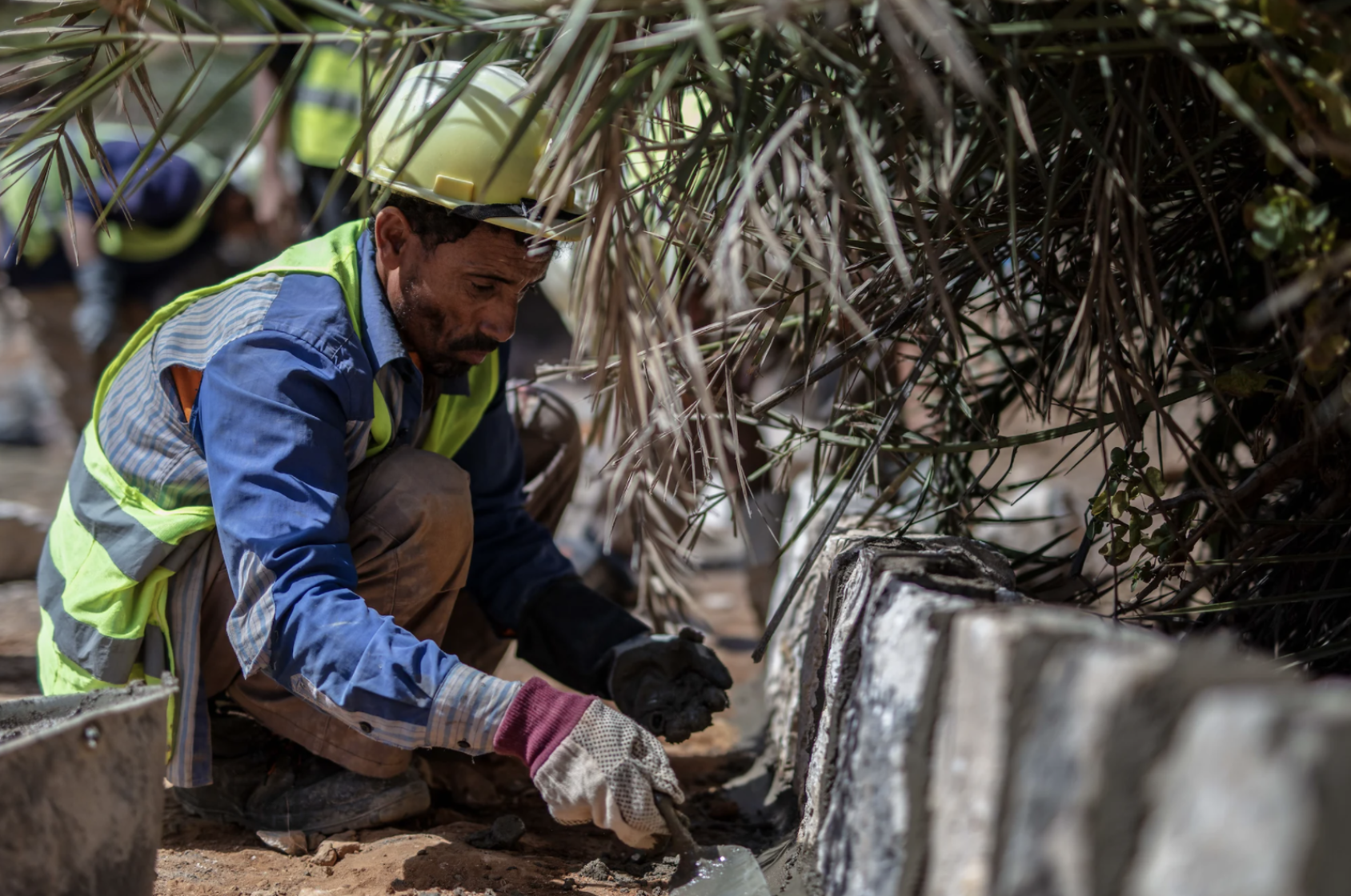 Hombre agachado mientras realiza trabajos manuales sobre la vía en construcción.