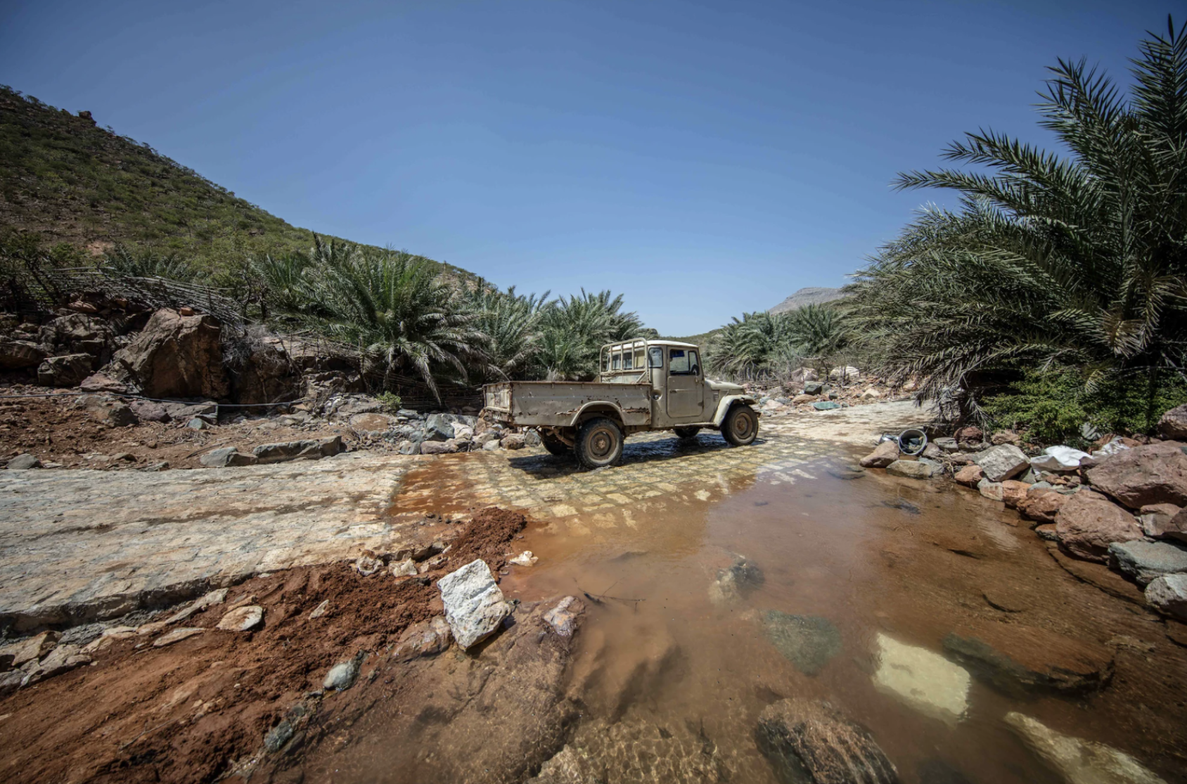 Un camión circulando por una calle parcialmente destruida.