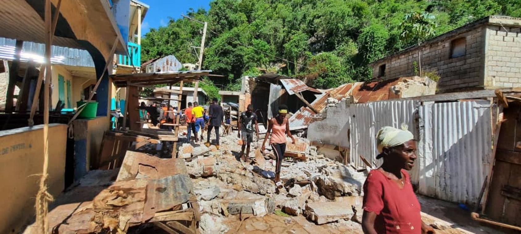 Des habitants de la localité de Pestel, en Haïti, déambulent dans une rue bordée de maisons détruites et jonchée de débris laissés par le séisme qui a frappé le pays en août 2021.