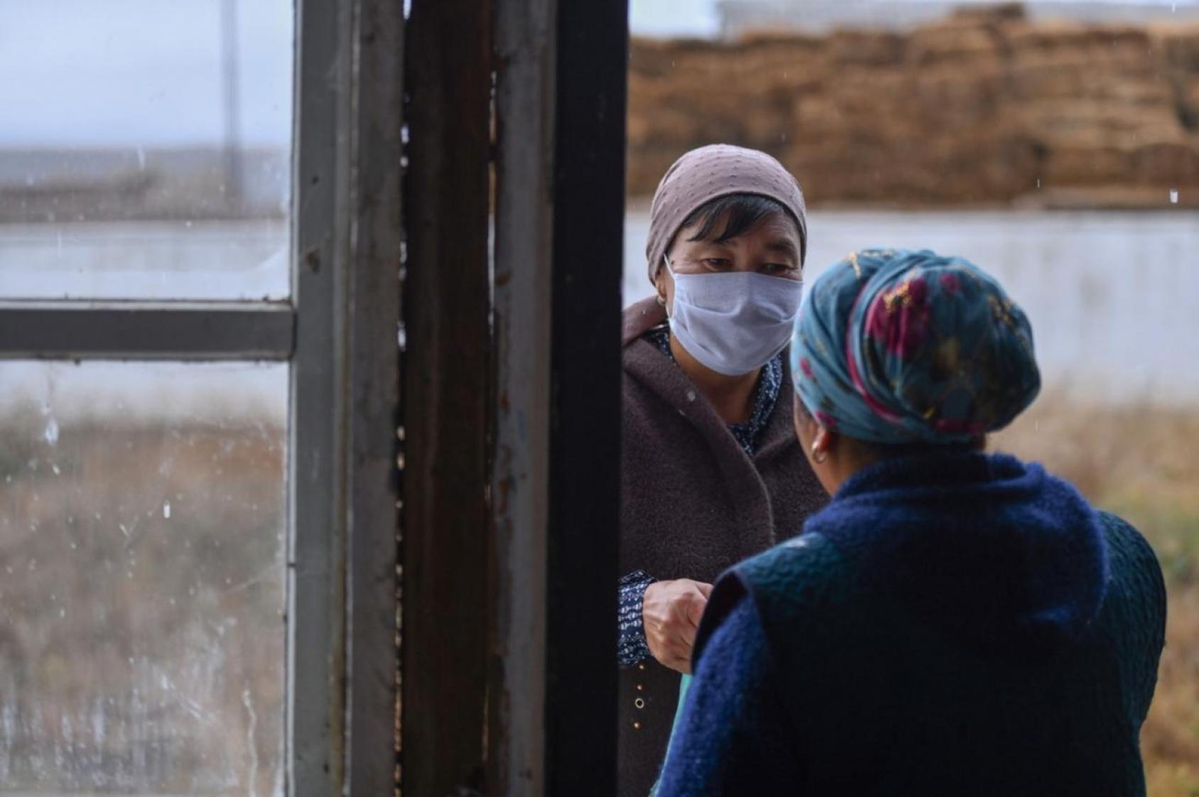 Deux femmes discutent près de l'entrée d'un immeuble.