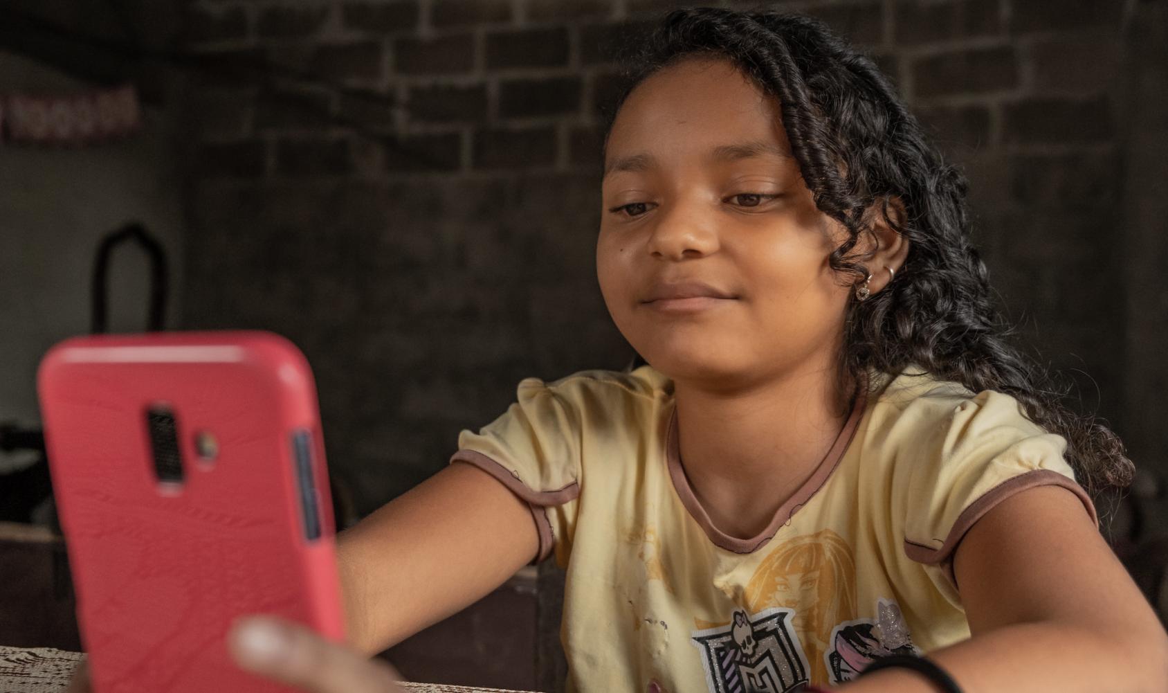 Une petite fille manipule un téléphone portable de couleur rose.