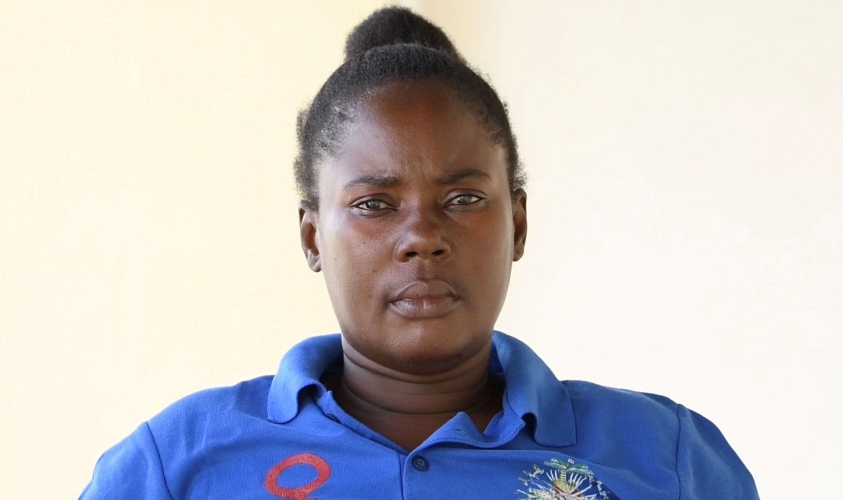 Une femme portant un t-shirt bleu et les cheveux coiffés en chignon regarde droit dans l'objectif.