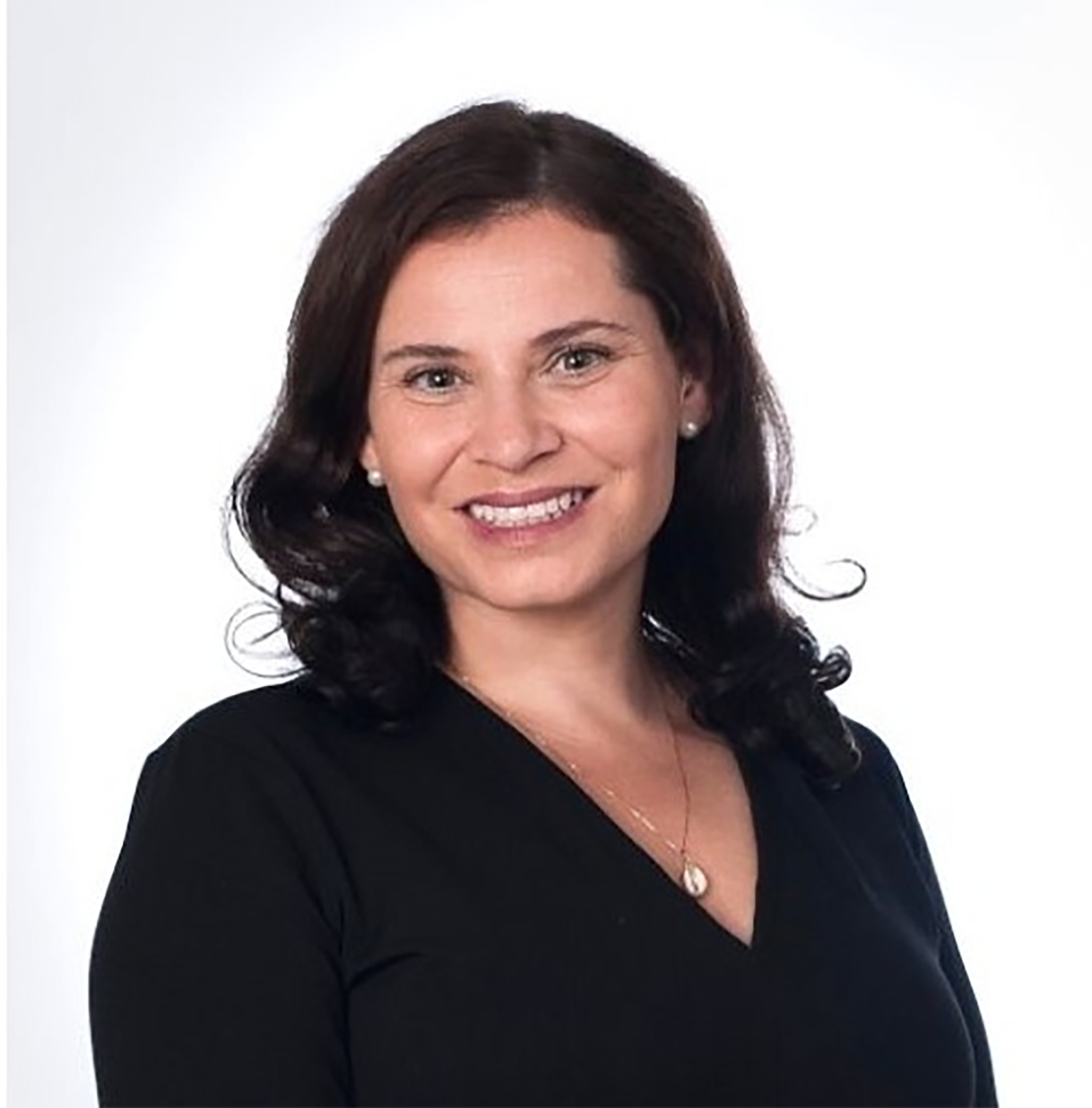 Una mujer con un traje negro mira directamente a la cámara.