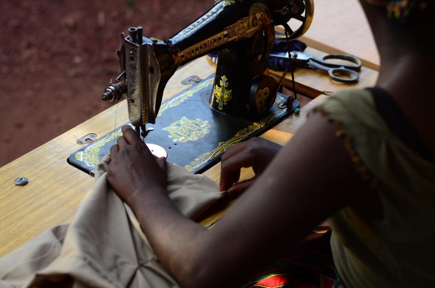 An image of a girl's hands while she works on a sewing machine.